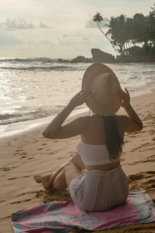 the woman sits on a towel at the beach