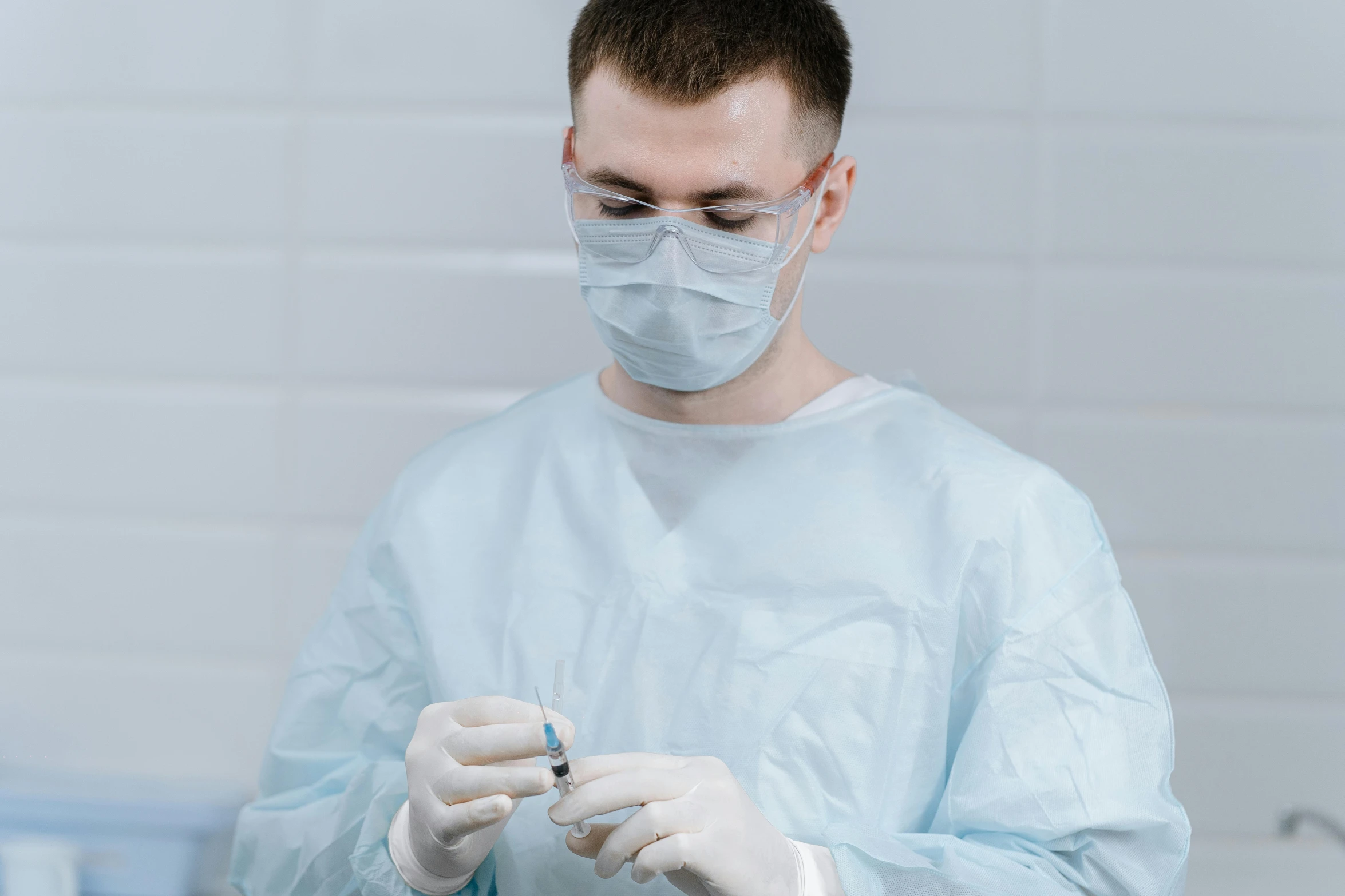 man wearing a blue gown injecting soing into his mouth