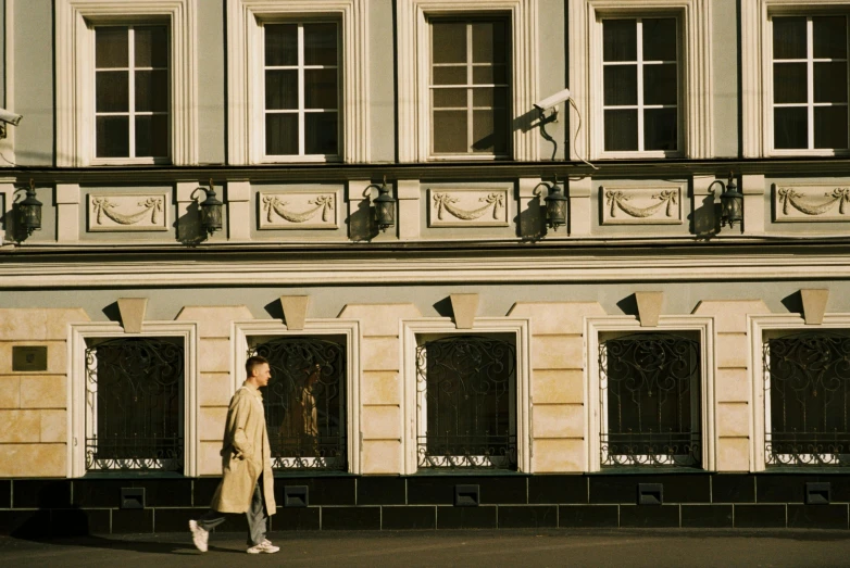 a woman walking down a city street past tall buildings