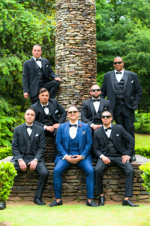 a group of men wearing suit and sunglasses sitting next to each other