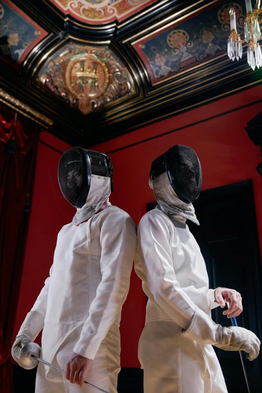 two people in fencing suits are holding swords