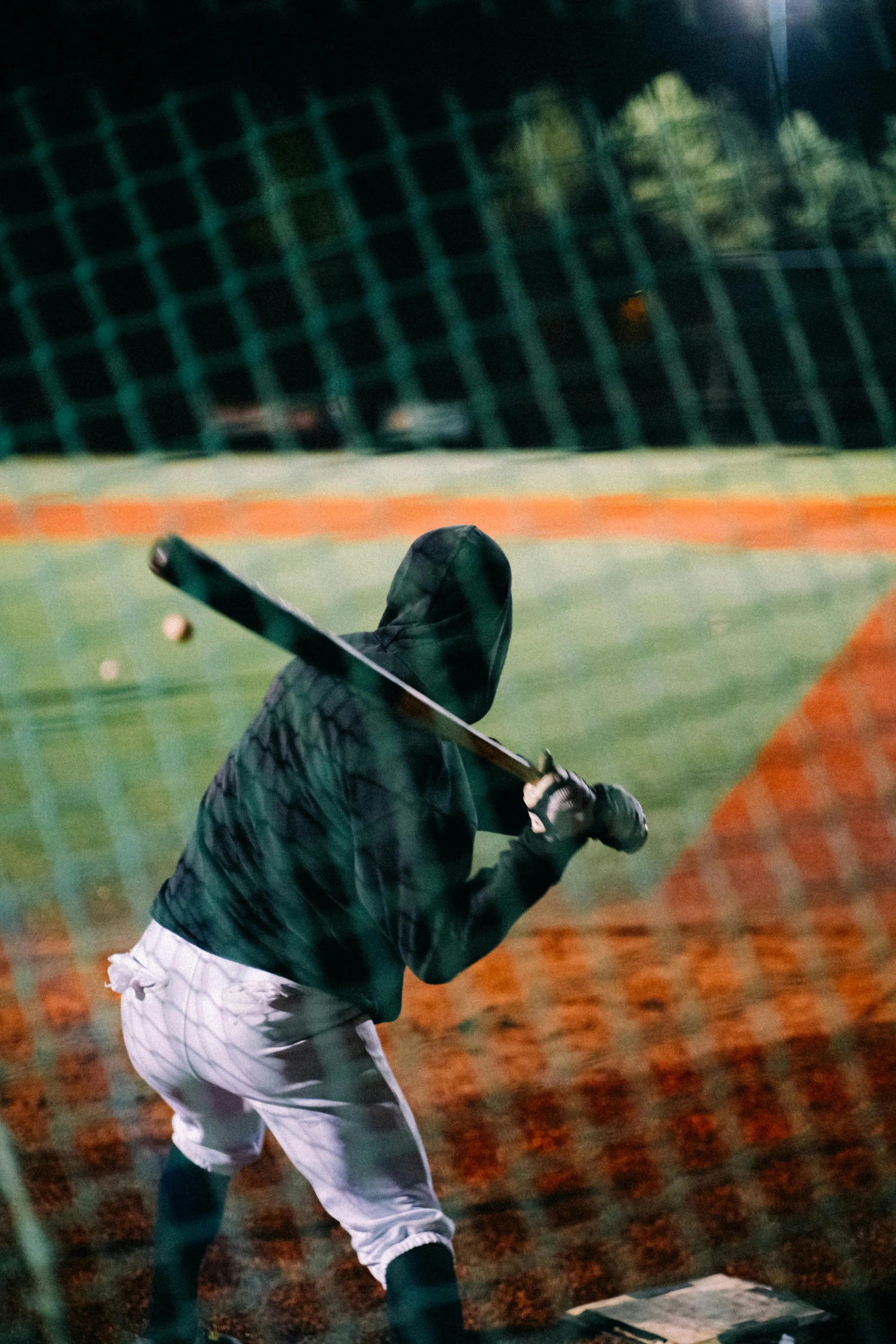 the baseball player in the black hooded sweatshirt is holding a baseball bat