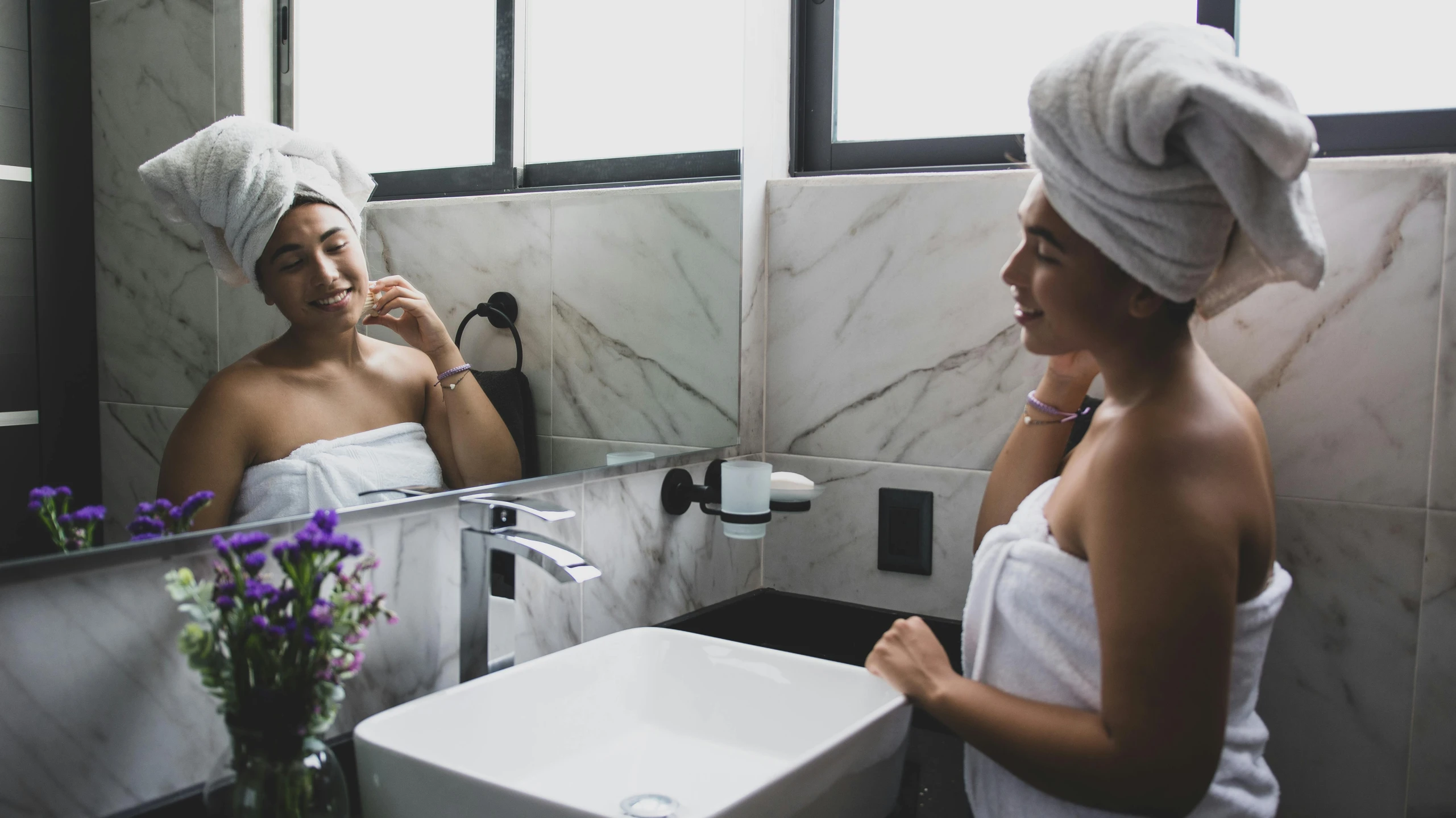 a woman in a towel looking at her face in the mirror