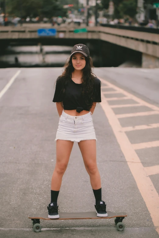 a girl on a skateboard stands on the road