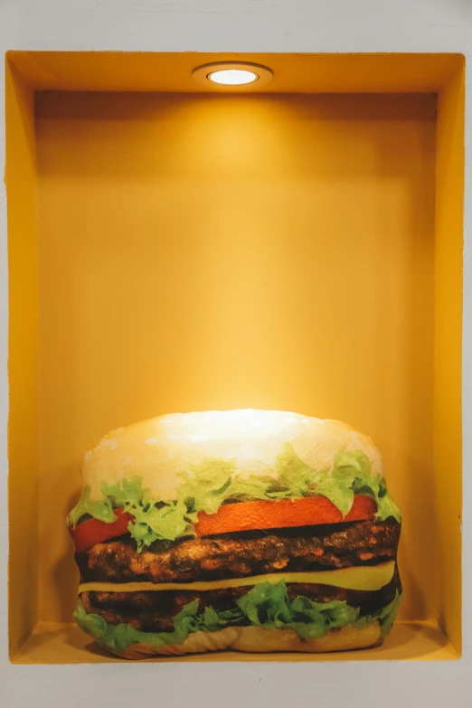 a large hamburger sitting in a yellow cardboard box