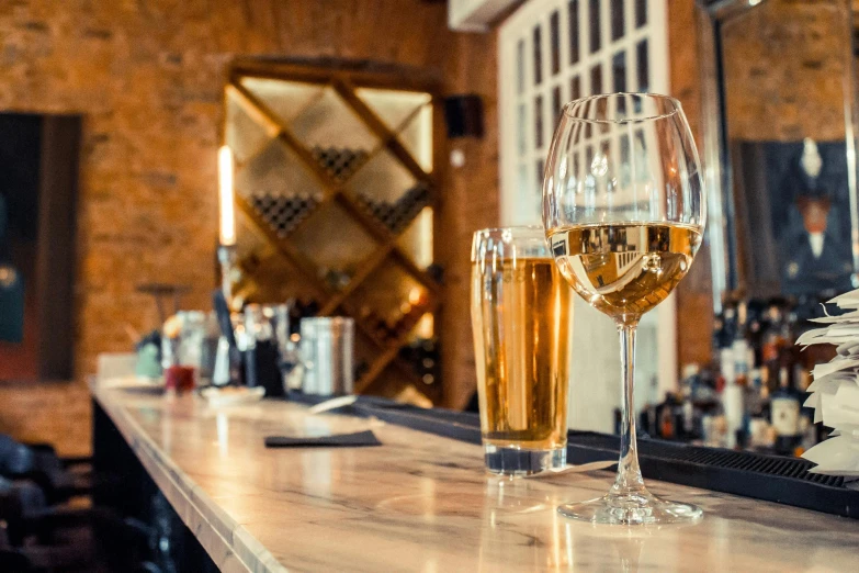 two wine glasses are on a bar with a newspaper