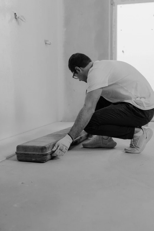 a man cleans the floor in the room with his foot