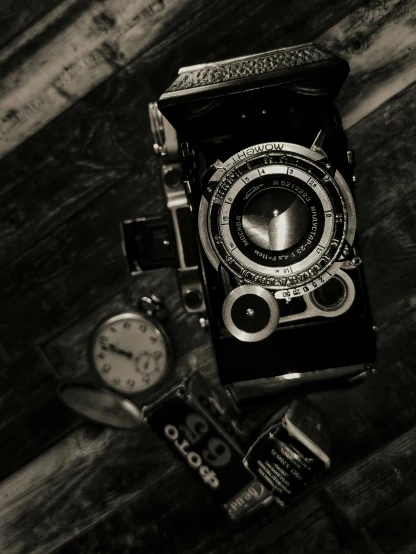 old fashioned antique cameras sitting beside a watch