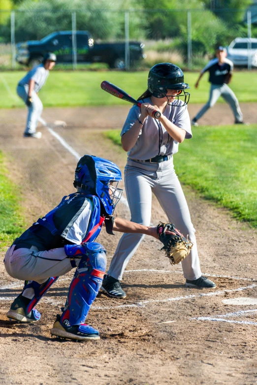 a catcher is up to catch a baseball while another person prepares to hit it