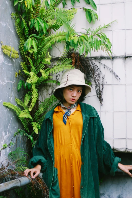 a woman wearing an orange dress stands in front of a green plant