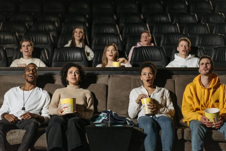 people sitting in a row and looking into the distance while holding cups