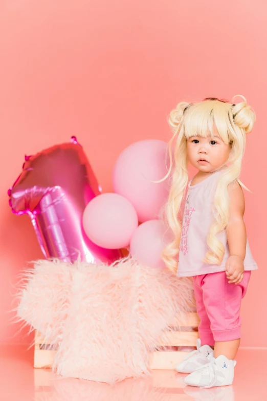 a  in pink stands next to pink balloons