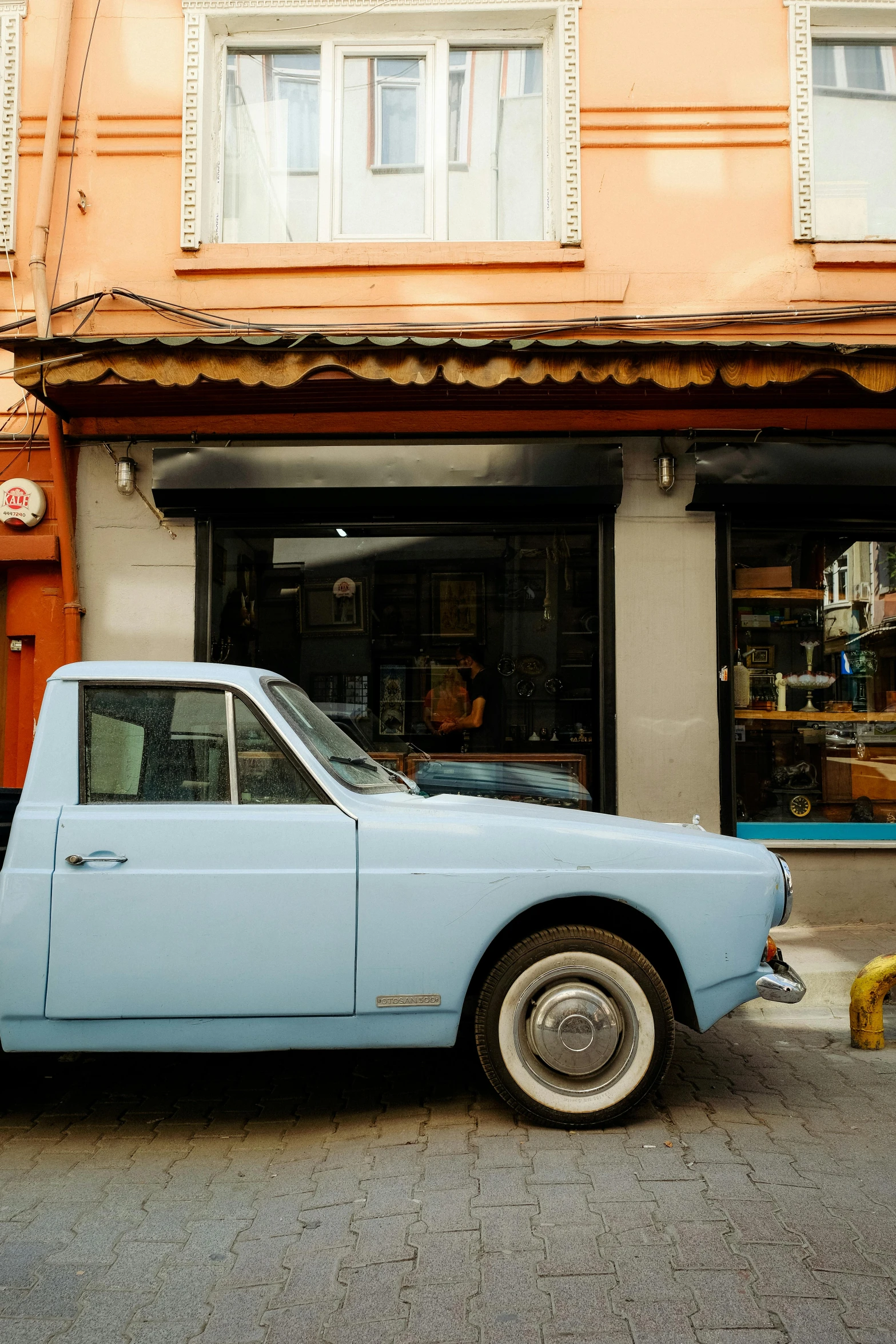 a blue vintage car parked in front of a small building