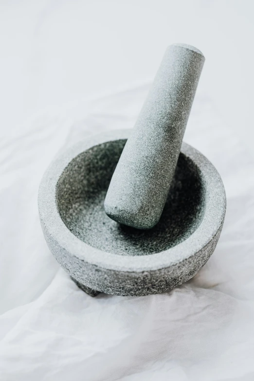 a stone mortar bowl with a handle on white bed linen