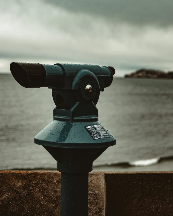 a coin meter sitting next to the ocean under a cloudy sky