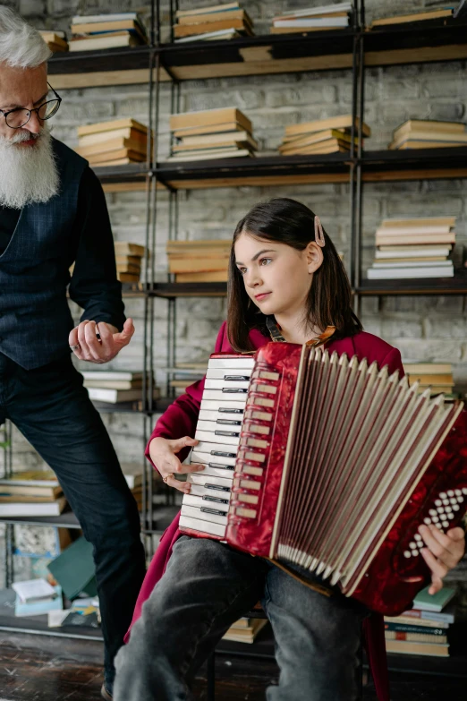 an old man is holding an accordion as a girl sits next to it