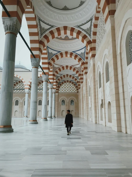 a man in a white and red hallway between arches