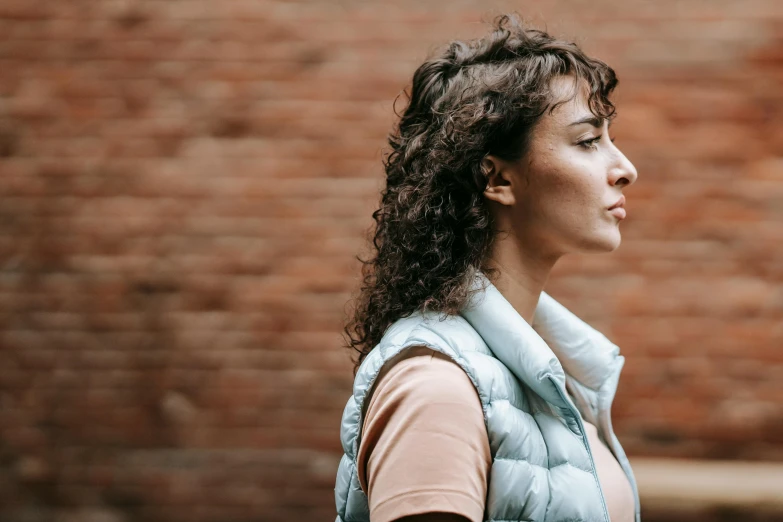 a woman with curly hair in a light blue vest