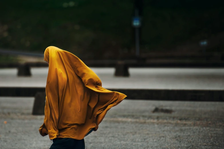 woman in yellow covering herself standing on a street