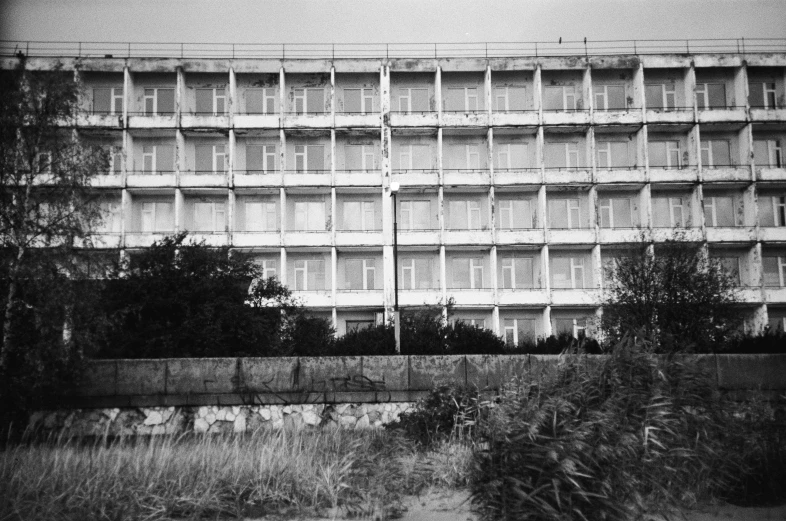 an old building sitting near some plants and water