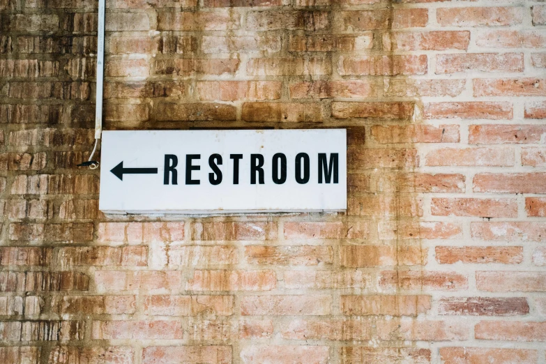 a sign on the side of a building pointing to restroom