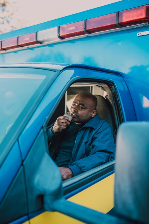 a man sitting inside of a blue truck drinking out of a bottle