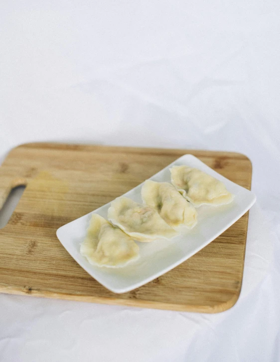 a wooden serving platter holding dumplings on it