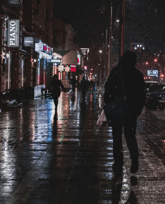 pedestrians in the rain walking down a city street