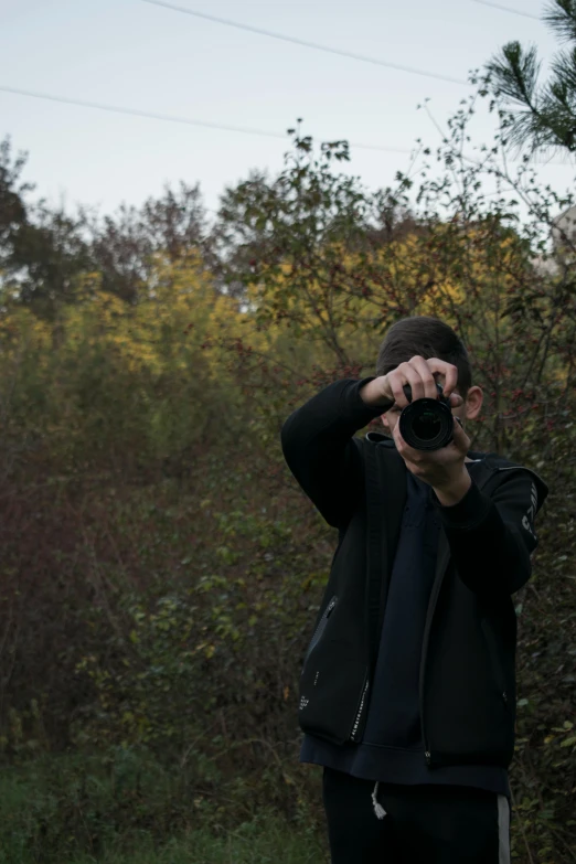 the man takes a picture while holding up a camera