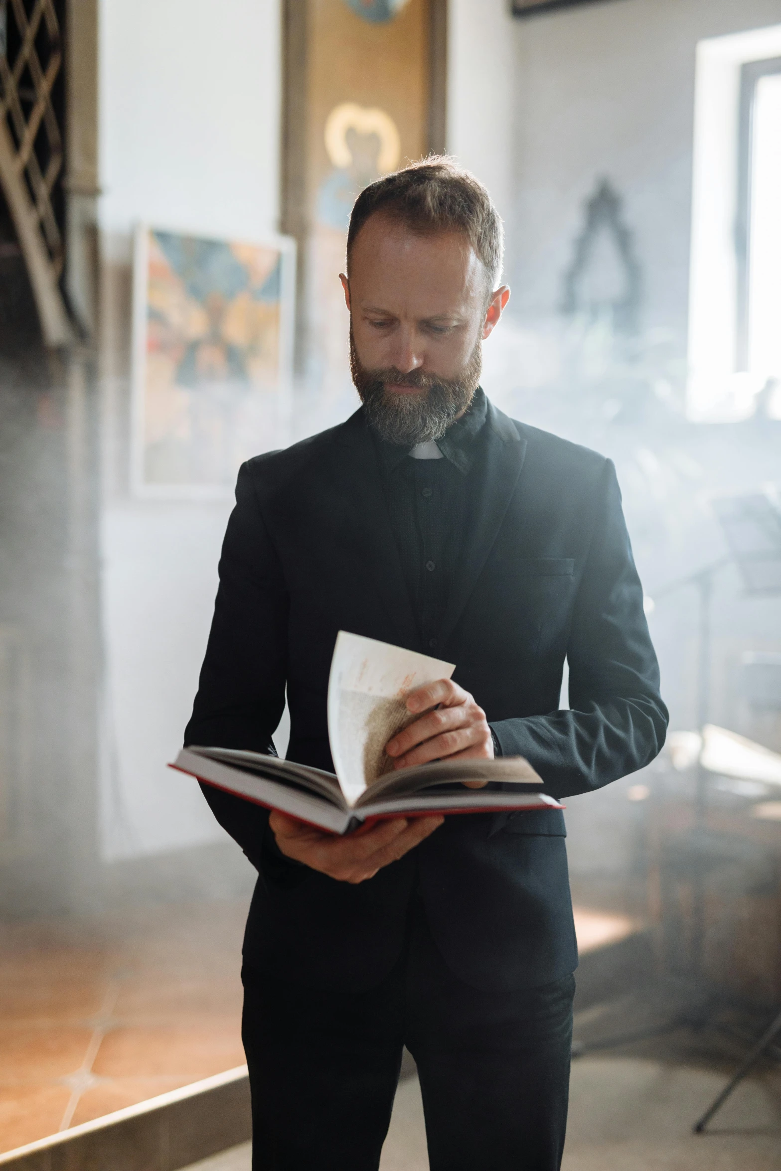 a man reading a book with the light reflecting off his coat