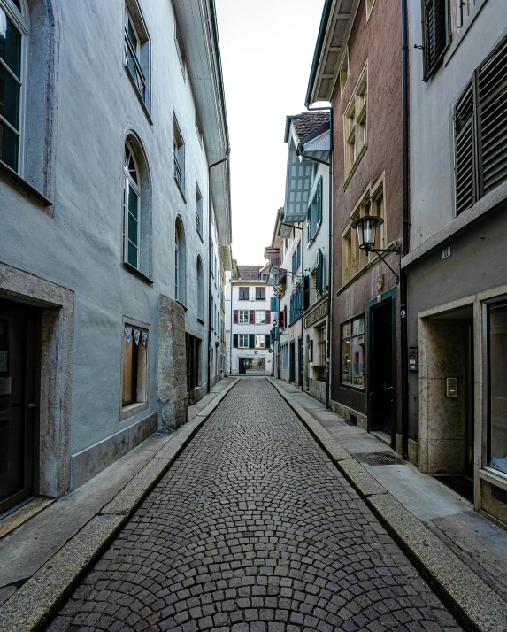 an empty cobblestone street surrounded by stone buildings