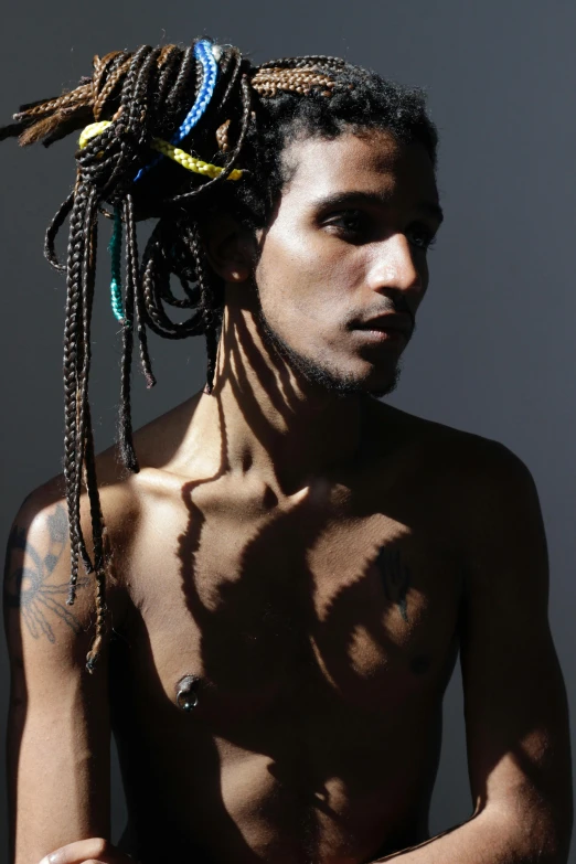 a shirtless man with dreads in his hair