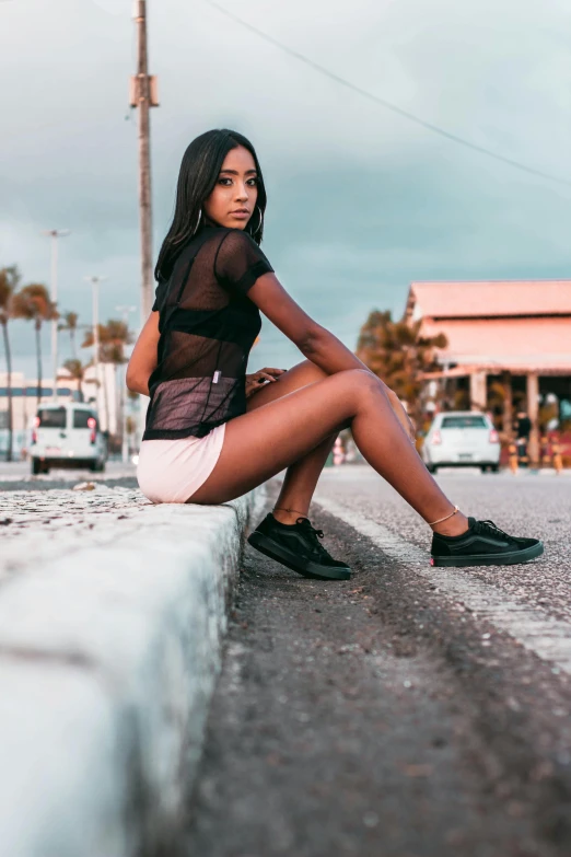 a woman wearing short skirts sits on the curb