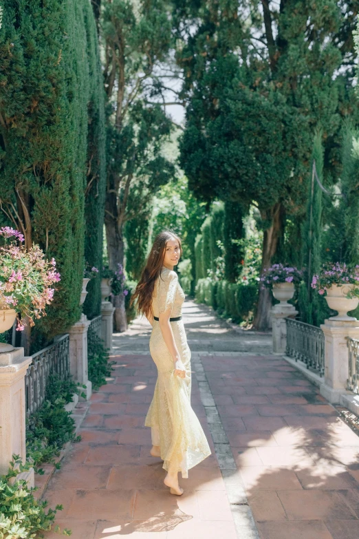 a woman wearing a yellow dress walking along a stone pathway