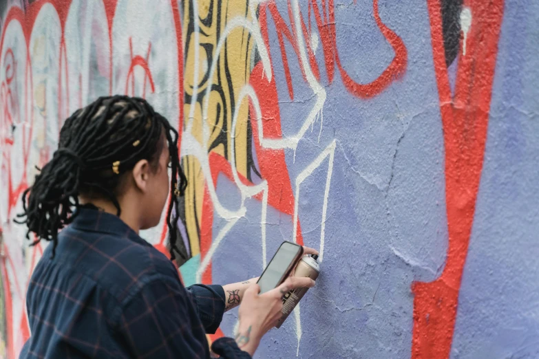 the woman is using her smart phone on the graffiti covered wall