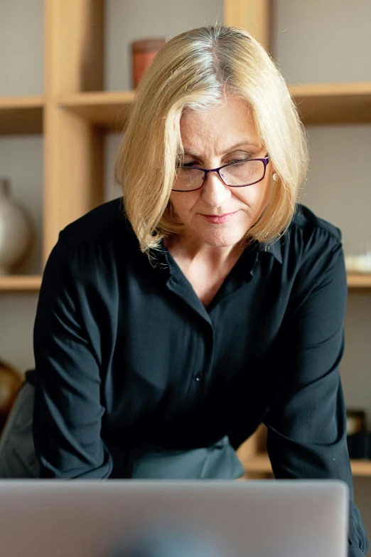 an older woman is sitting in front of a laptop