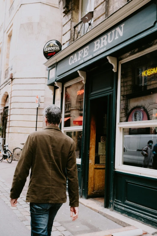 a man walks down the sidewalk towards a cafe