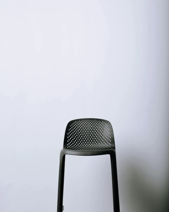 a black chair and white wall in the corner