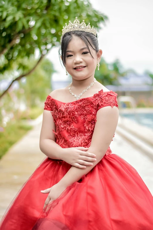 a little girl dressed in red and posing for a picture