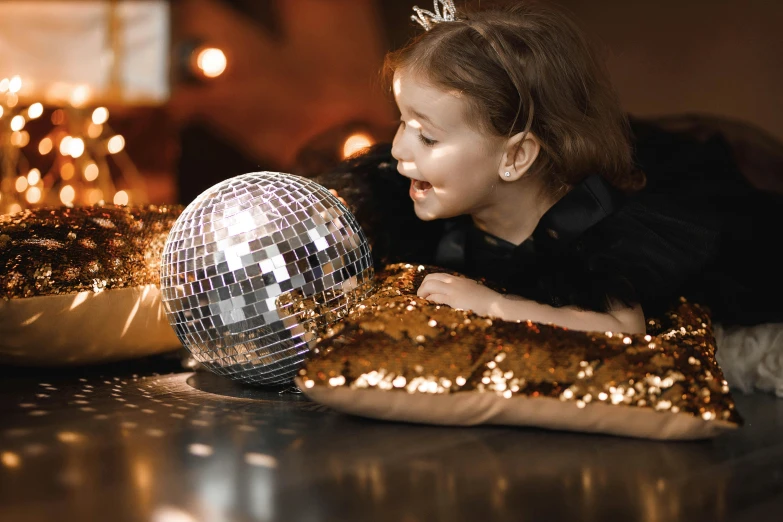 the little girl looks at a disco ball on top of a pillow