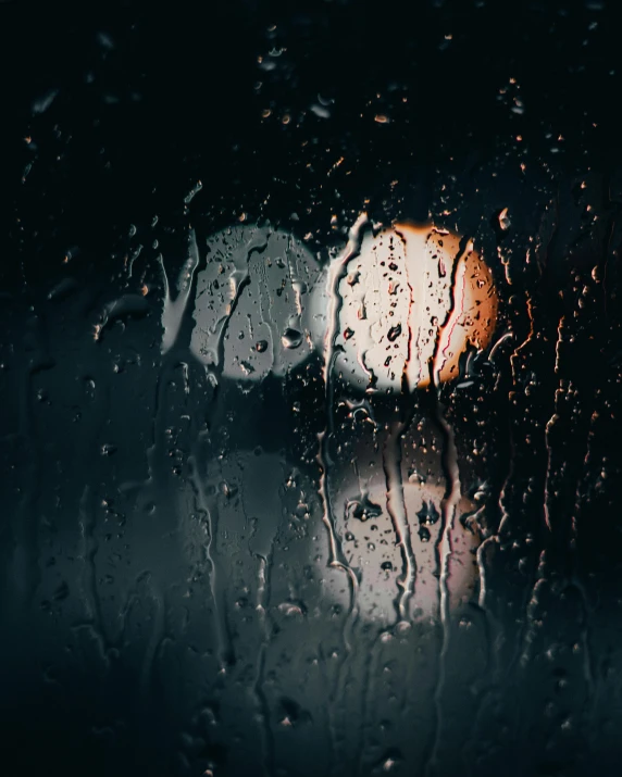 the view through a rainy windshield of some street lights