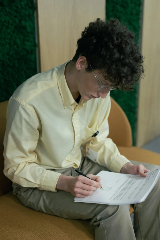 a man sitting down writing on a piece of paper