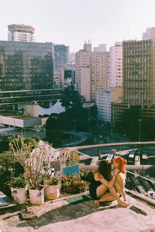 two people hug on a building rooftop next to city