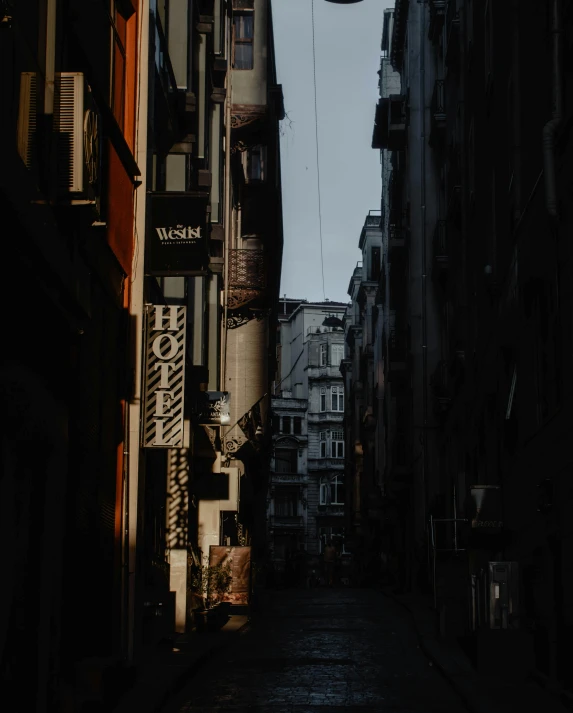a narrow alley with hanging signs on a cloudy day