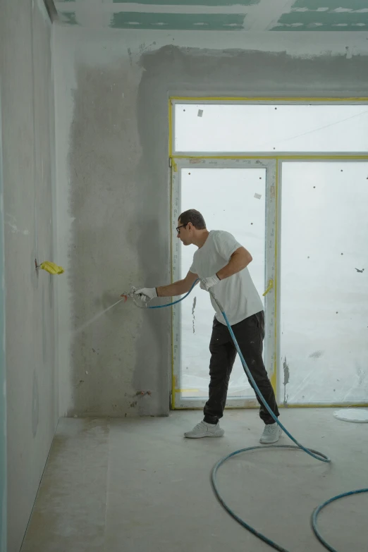 man washing up the wall in an unfinished room