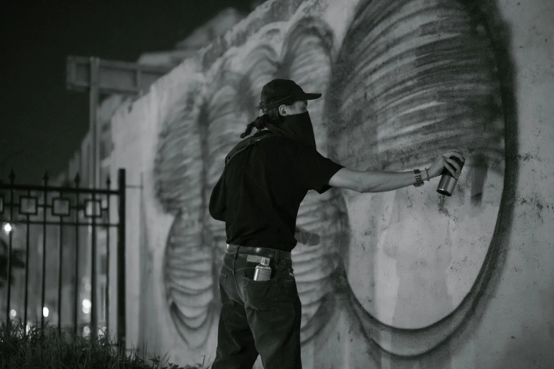 the man is painting the wall with some graffiti