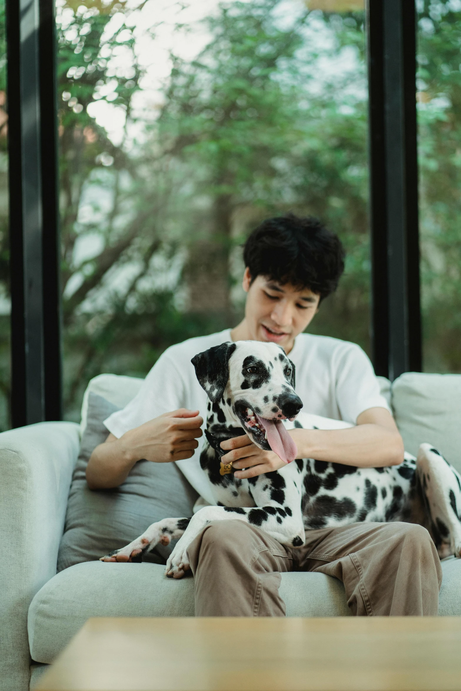 man sitting on a couch holding a dalmatian puppy