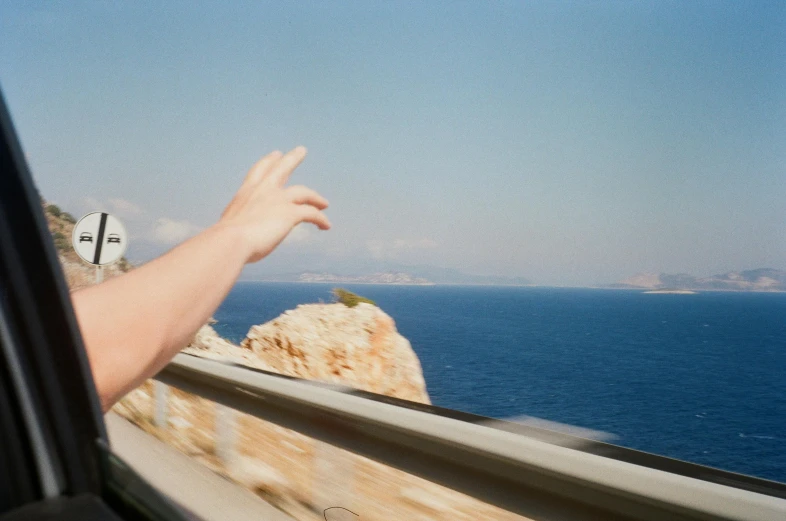 view out the window of a vehicle with a man leaning against it and reaching for soing