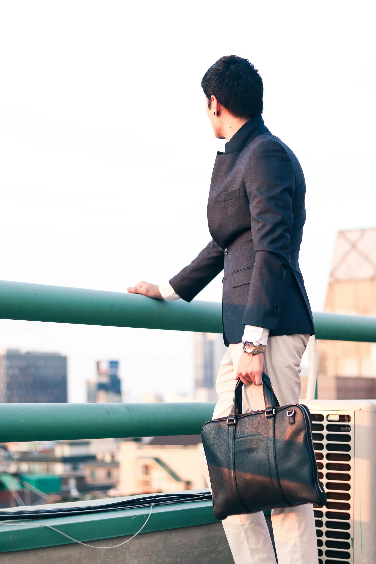 a man is holding onto his handbag while walking down the bridge