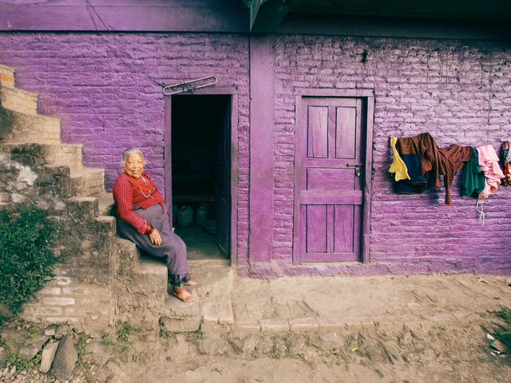 a person sitting in front of purple wall with clothes drying out